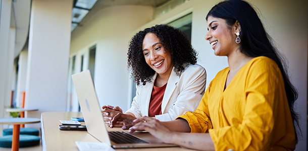 Two businesswomen working together at a desk with a laptop